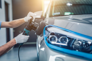 Car detailing - Man holds a polisher in the hand and polishes the car. Selective focus.